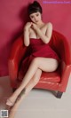 A woman in a red dress sitting on a red chair.