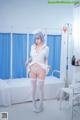 A woman dressed as a nurse standing in a hospital room.