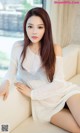A woman sitting on a couch in a white sweater.
