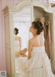 A woman in a wedding dress sitting in front of a mirror.