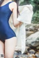 A woman in a blue bathing suit standing next to a stream.