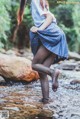 A woman in a plaid skirt is standing in a stream.