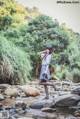 A woman standing on a rock in a stream.