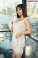 A woman in a white dress standing on a balcony.