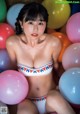 A woman in a bikini sitting in a bunch of balloons.