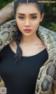 A woman holding a large snake in her hands.