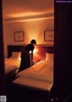 A woman standing in a hotel room next to two beds.