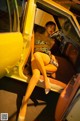 A woman sitting in the driver's seat of a yellow car.