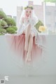 A woman in a wedding dress sitting on a window sill.