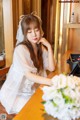 A woman sitting at a table with a bouquet of flowers.