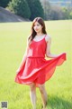 A woman in a red dress standing in a field.