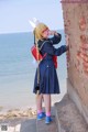 A woman in a school uniform leaning against a brick wall.