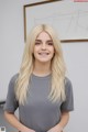 A woman with long blonde hair standing in front of a whiteboard.