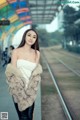 A woman in a fur coat standing on a train track.