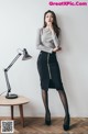 A woman standing next to a table with a lamp on it.