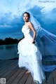 A woman in a wedding dress standing on a dock.