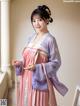 A woman in a pink and purple hanbok is posing for a picture.